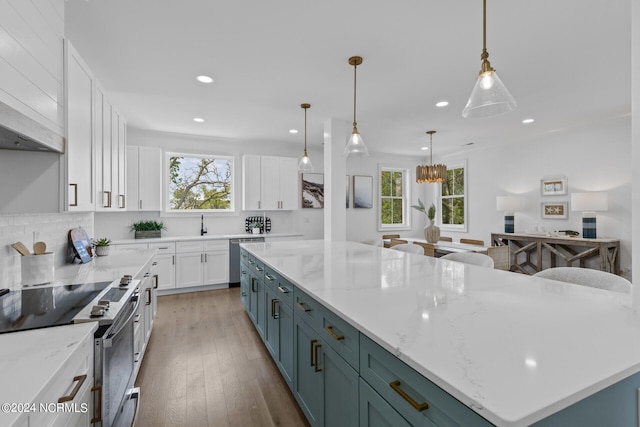 kitchen featuring white cabinetry, a large island, decorative light fixtures, decorative backsplash, and appliances with stainless steel finishes