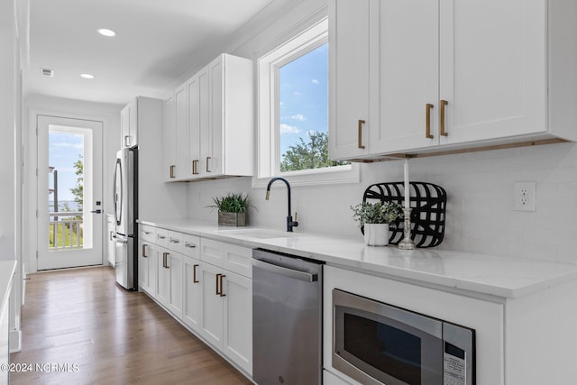 kitchen with white cabinetry, sink, light stone countertops, and appliances with stainless steel finishes