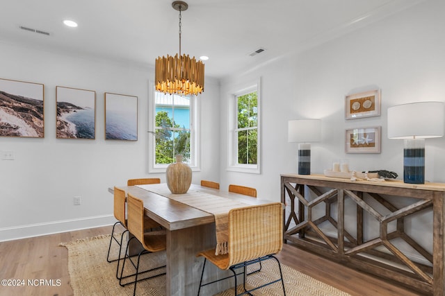 dining space with an inviting chandelier, light hardwood / wood-style flooring, and crown molding