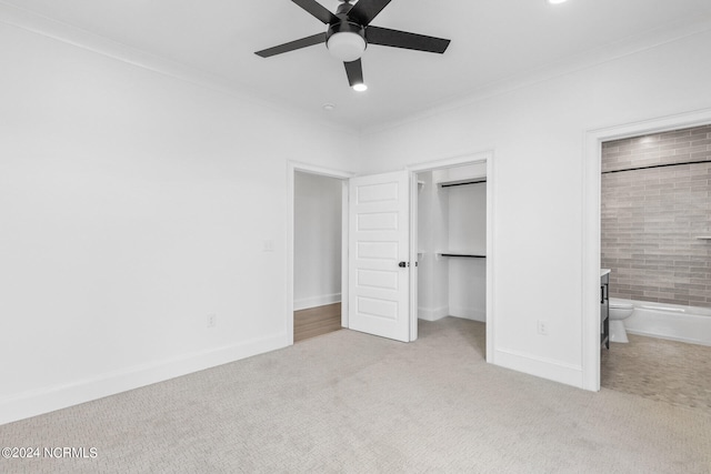 unfurnished bedroom featuring ensuite bathroom, crown molding, ceiling fan, light colored carpet, and a closet