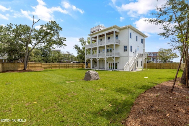 rear view of house with a balcony, a patio area, and a lawn