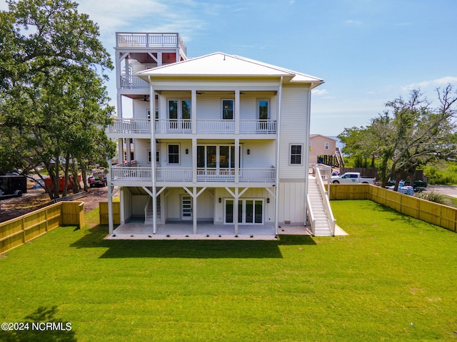 rear view of house featuring a lawn, a balcony, and a patio