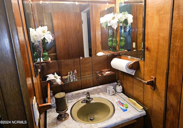 bathroom featuring wooden walls and sink