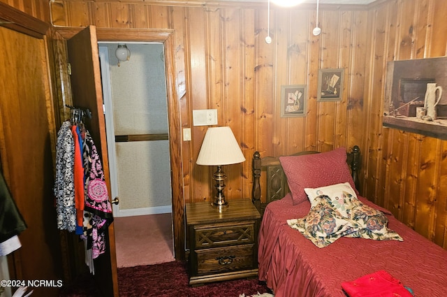 carpeted bedroom featuring wood walls