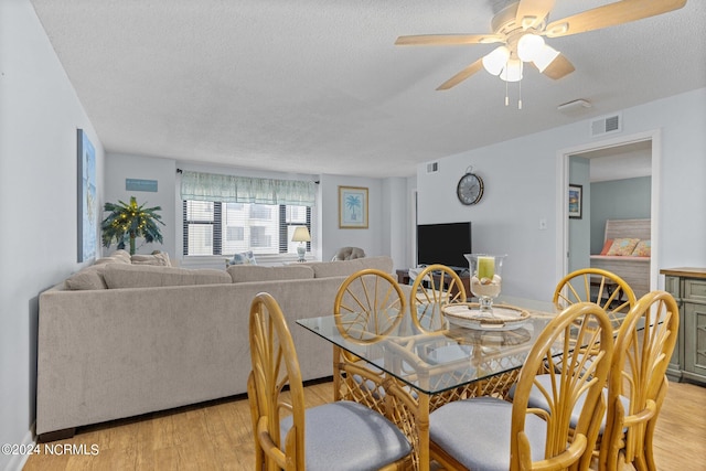 dining space with a textured ceiling, ceiling fan, and light wood-type flooring