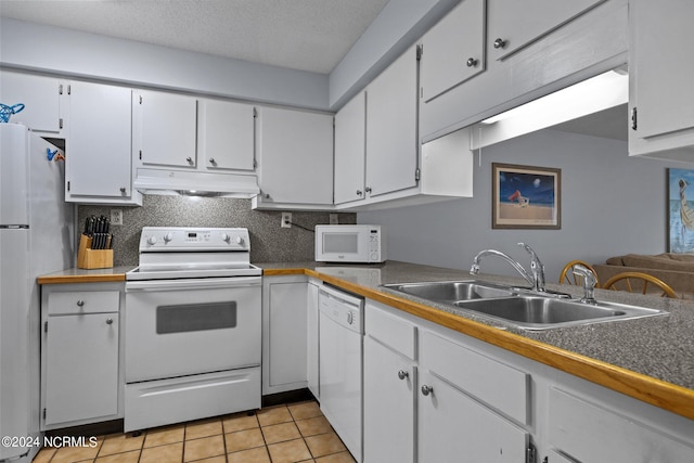 kitchen featuring light tile floors, white cabinetry, sink, white appliances, and a textured ceiling