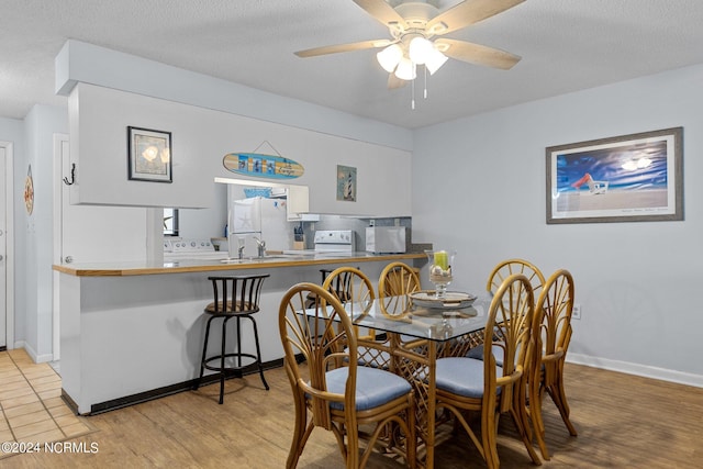 dining space with a textured ceiling, light wood-type flooring, and ceiling fan