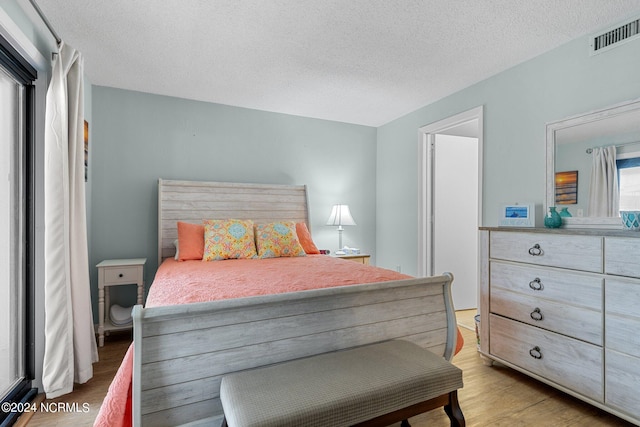 bedroom with a textured ceiling and light hardwood / wood-style flooring