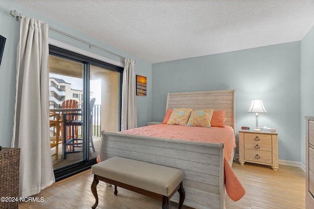 bedroom with a textured ceiling, light wood-type flooring, and access to outside