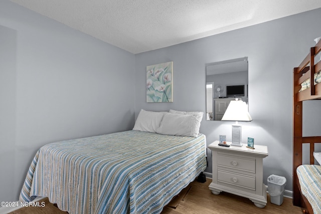 bedroom with a textured ceiling and hardwood / wood-style floors