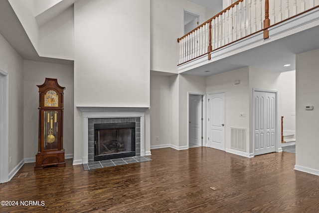 unfurnished living room with a fireplace, dark wood-type flooring, and a high ceiling