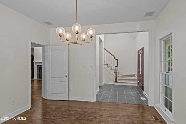 unfurnished dining area featuring a notable chandelier and dark hardwood / wood-style floors