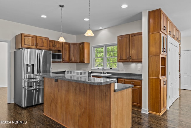 kitchen with sink, hanging light fixtures, dark hardwood / wood-style floors, appliances with stainless steel finishes, and a kitchen island