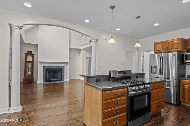 kitchen featuring hanging light fixtures, dark hardwood / wood-style flooring, decorative columns, a tiled fireplace, and appliances with stainless steel finishes