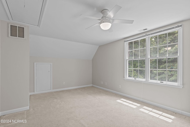 additional living space with light carpet, plenty of natural light, lofted ceiling, and ceiling fan