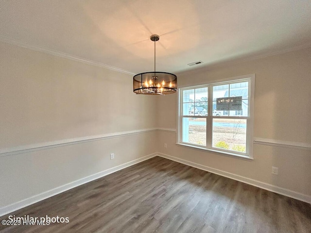 spare room with a chandelier, ornamental molding, and dark hardwood / wood-style floors