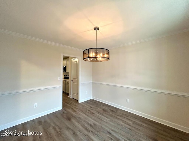 empty room featuring dark wood-type flooring, ornamental molding, and a chandelier