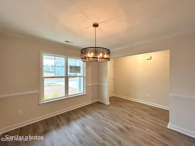 unfurnished dining area with an inviting chandelier, crown molding, and hardwood / wood-style floors