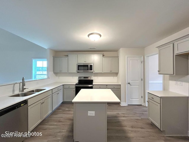 kitchen with dark hardwood / wood-style floors, gray cabinets, a center island, sink, and stainless steel appliances