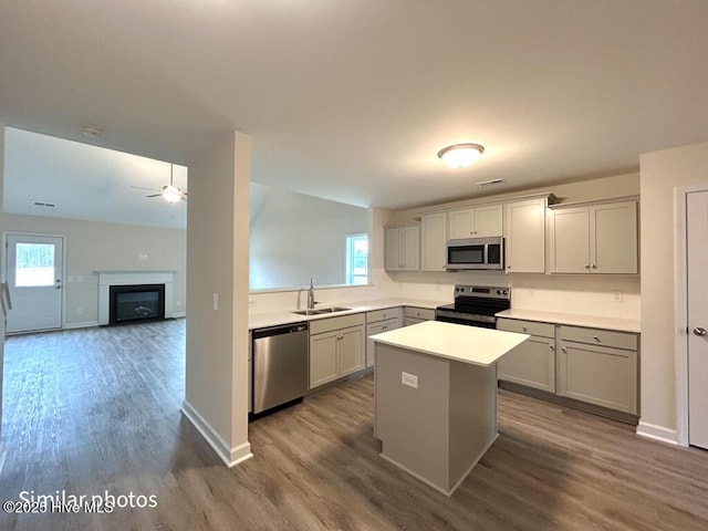 kitchen featuring gray cabinets, a kitchen island, wood-type flooring, sink, and appliances with stainless steel finishes