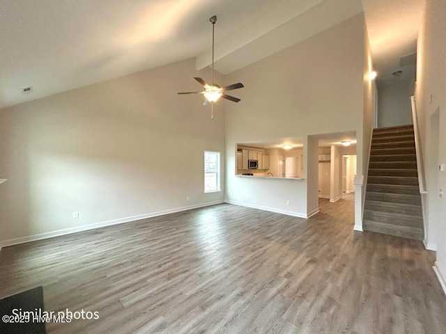 unfurnished living room featuring dark wood-type flooring, ceiling fan, beam ceiling, and high vaulted ceiling