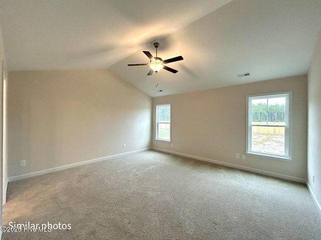 carpeted spare room featuring ceiling fan, a wealth of natural light, and lofted ceiling