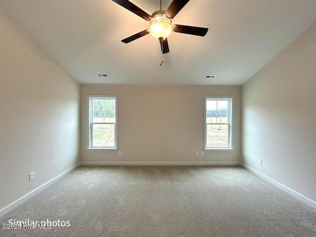 carpeted spare room with ceiling fan and a wealth of natural light