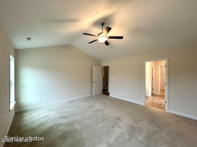 carpeted spare room with ceiling fan and vaulted ceiling