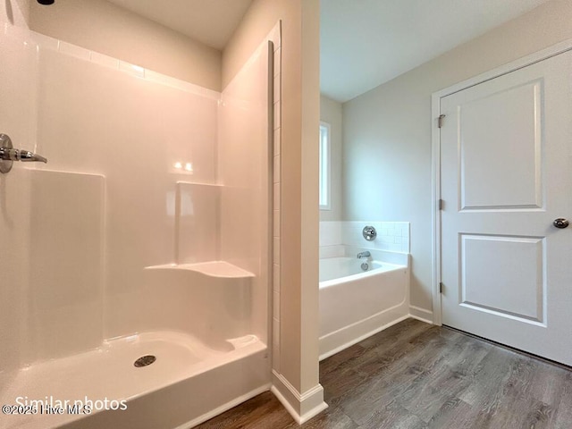 bathroom with hardwood / wood-style flooring and shower with separate bathtub