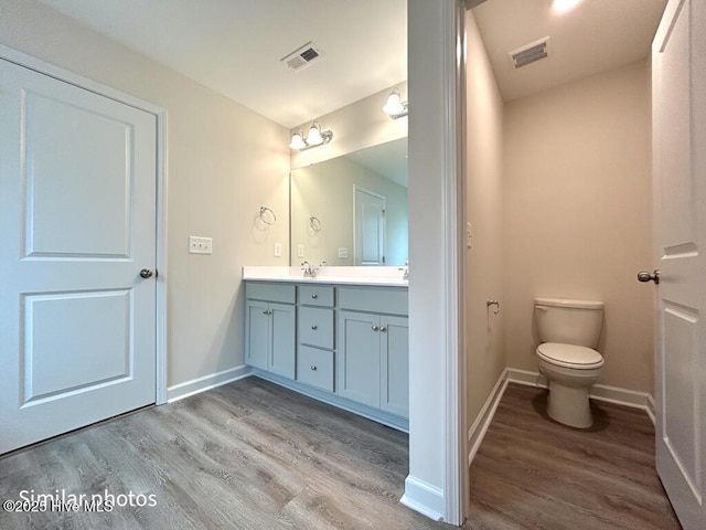 bathroom with toilet, hardwood / wood-style floors, and vanity