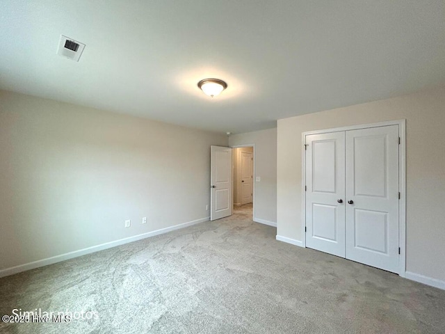 unfurnished bedroom with light carpet and a closet