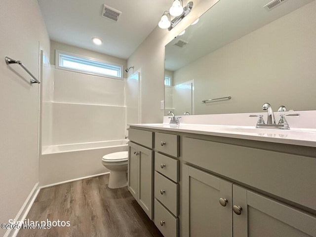 full bathroom with toilet, wood-type flooring, vanity, and washtub / shower combination