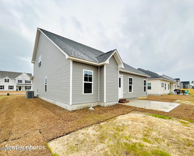 rear view of house featuring central AC unit, a patio area, and a yard