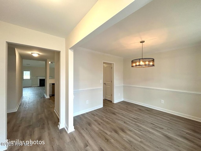 spare room featuring dark hardwood / wood-style floors, crown molding, and a notable chandelier