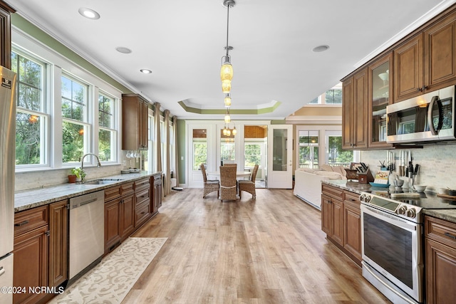 kitchen with light stone countertops, stainless steel appliances, plenty of natural light, and hanging light fixtures