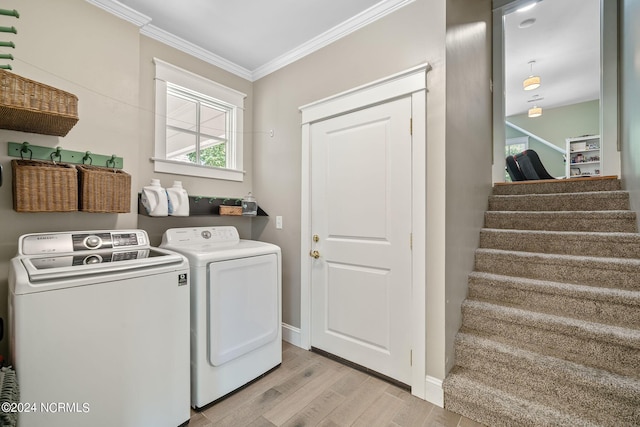 laundry area featuring washer and dryer, light hardwood / wood-style floors, and ornamental molding