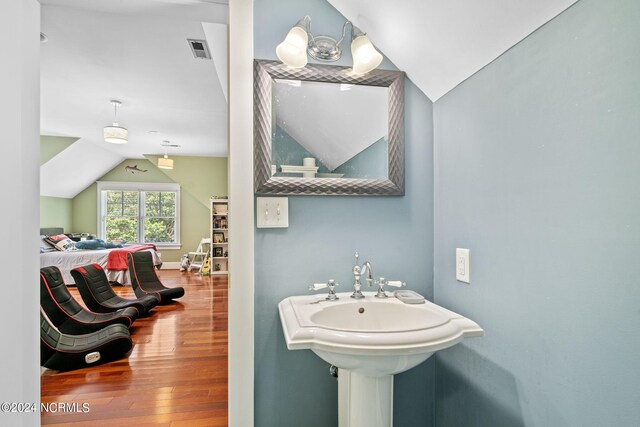 bathroom featuring hardwood / wood-style floors, sink, and vaulted ceiling