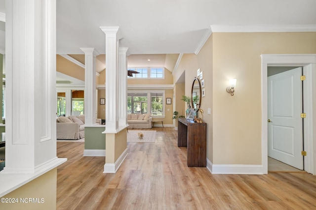 foyer featuring decorative columns, crown molding, and light hardwood / wood-style flooring