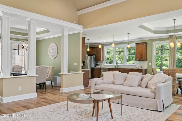 living room with sink, ornamental molding, light hardwood / wood-style floors, and a notable chandelier