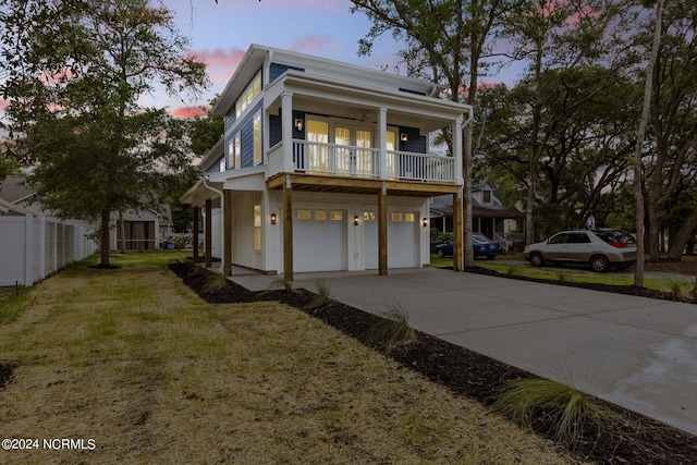 view of front of house featuring a garage, a yard, and a balcony