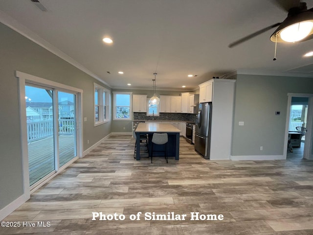 kitchen with pendant lighting, light countertops, appliances with stainless steel finishes, white cabinets, and a kitchen island