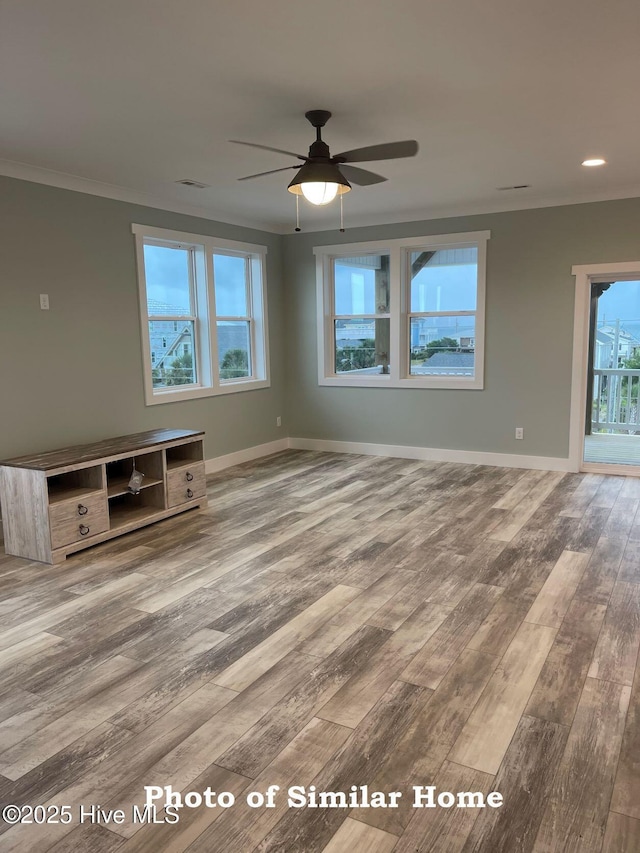 unfurnished living room with crown molding, baseboards, and wood finished floors