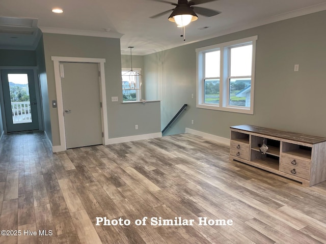 interior space featuring visible vents, baseboards, wood finished floors, crown molding, and ceiling fan with notable chandelier