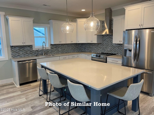 kitchen with stainless steel appliances, light countertops, a sink, and wall chimney exhaust hood