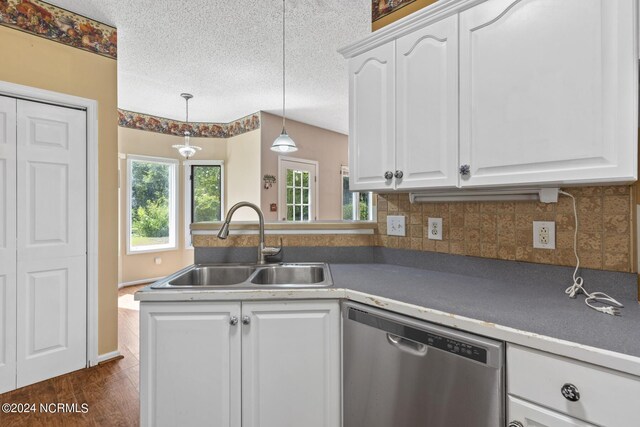 kitchen with a sink, white cabinetry, hanging light fixtures, stainless steel dishwasher, and dark countertops