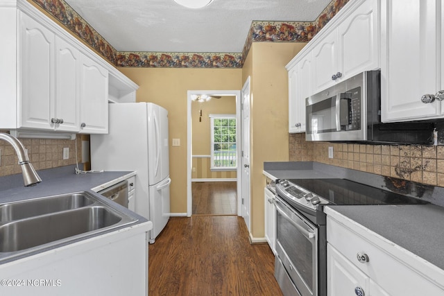 kitchen featuring dark countertops, white cabinetry, stainless steel appliances, and dark wood finished floors