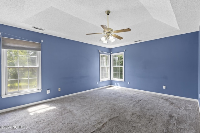 carpeted empty room with a textured ceiling, a ceiling fan, visible vents, and baseboards