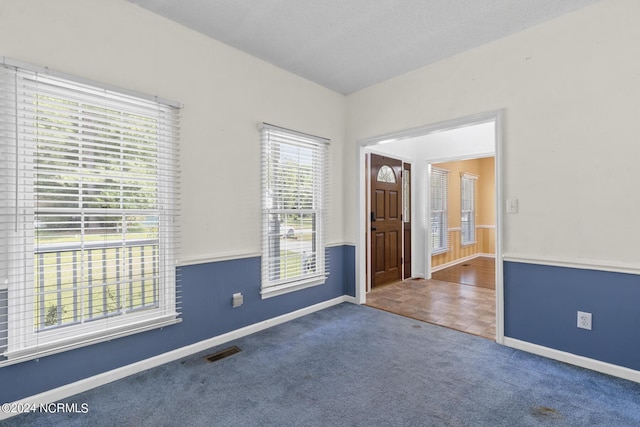 unfurnished room featuring carpet floors, baseboards, visible vents, and a textured ceiling