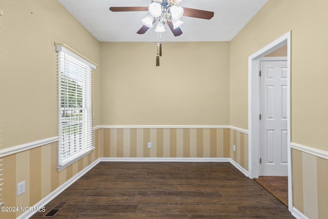 empty room with wallpapered walls, baseboards, visible vents, and dark wood finished floors