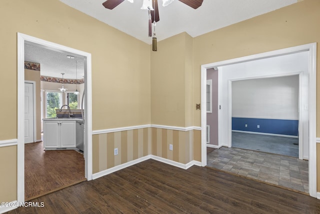 interior space with baseboards, a ceiling fan, dark wood-style flooring, a textured ceiling, and a sink